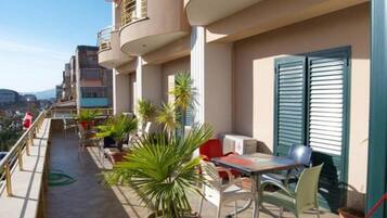 A balcony with outdoor furniture, potted plants, and a view of the city.