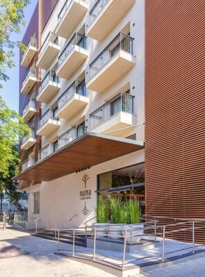 A multi-story hotel with balconies, a covered entrance, and a sign with a logo. - Numa Hotel Jaffa (Tel Aviv)