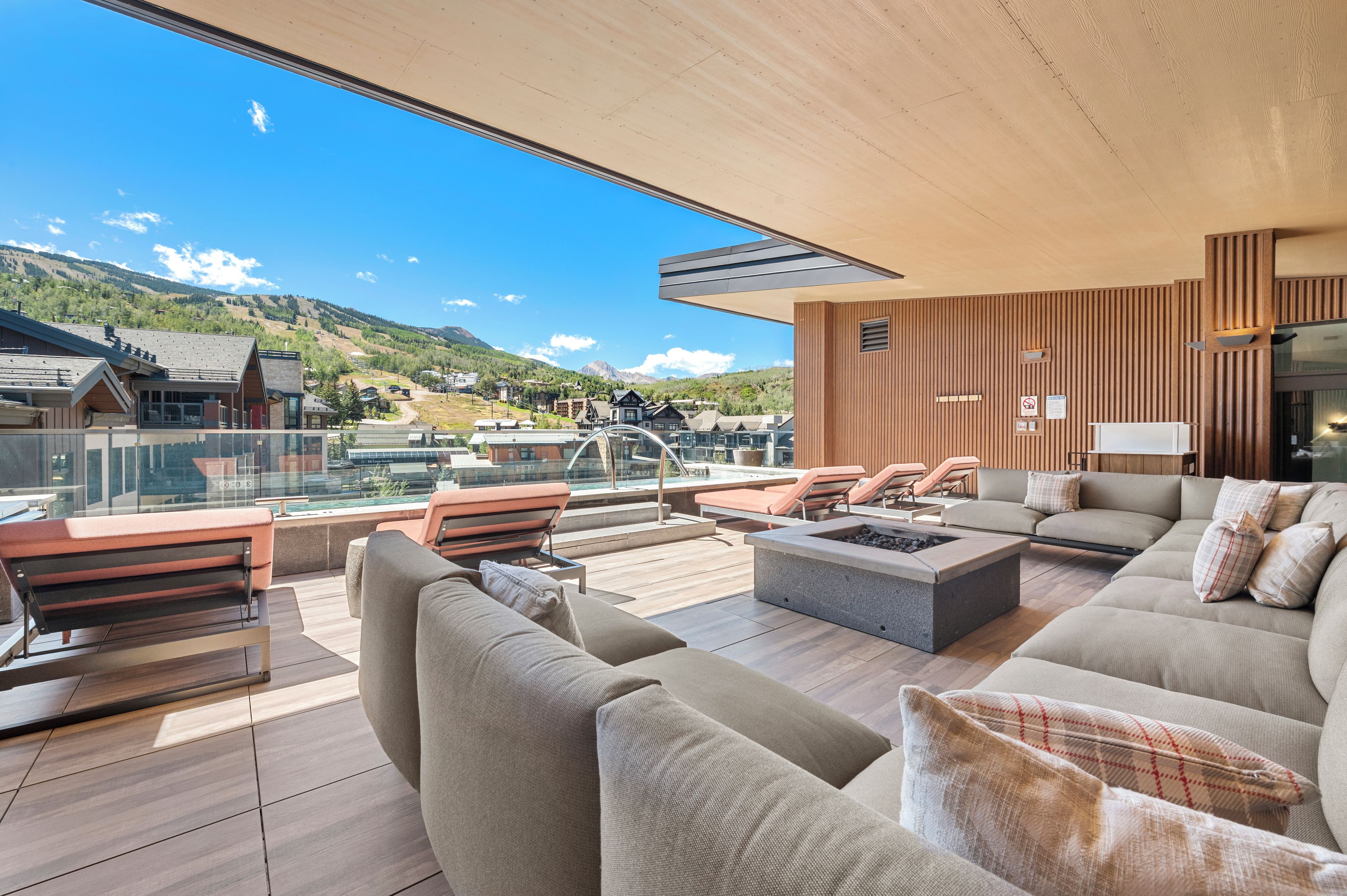 A modern outdoor lounge area with a pool, seating, and a view of the mountains.