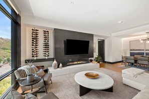 A modern living room with a fireplace, a flat-screen TV, and a wine rack. - Chateau Royale | One Snowmass East #605 | 4B/4B (Snowmass Village)