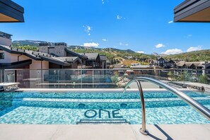 A swimming pool with a clear blue water feature and the word 'ONE' spelled out in the center. - Chateau Royale | One Snowmass East #605 | 4B/4B (Snowmass Village)