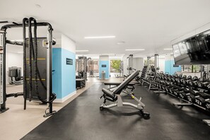 Ein Fitnessstudio mit verschiedenen Trainingsgeräten, darunter Kraftgeräte und Kurzhanteln.