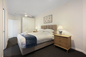A hotel room with a bed, bedside tables, a wardrobe, and a ceiling fan. - Tranquil Waterfront Retreat | Broadbeach Waters (Broadbeach Waters)
