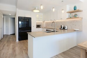 A modern kitchen with a central island, stainless steel appliances, and pendant lighting. - Tranquil Waterfront Retreat | Broadbeach Waters (Broadbeach Waters)