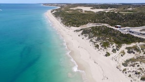 An aerial view of a beach with a road curving along the coastline.