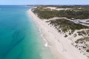 An aerial view of a beach with a road curving along the coastline.