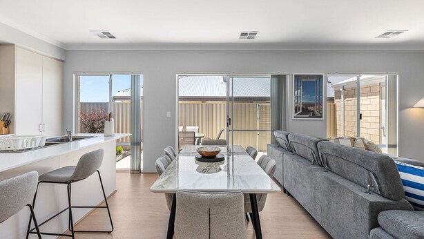 A modern kitchen with a dining area, a sofa, and a view of the outside.