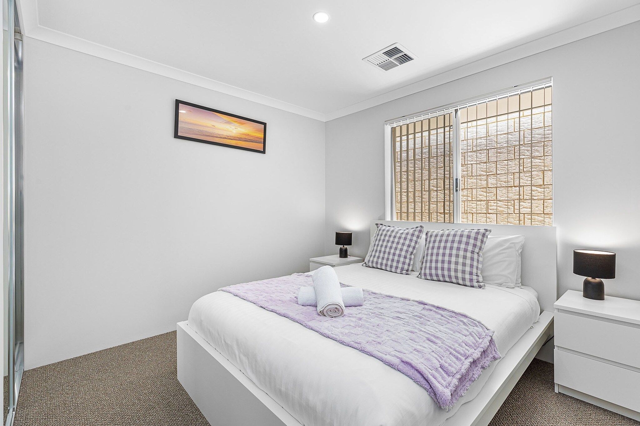 Une chambre à coucher moderne avec un lit, une fenêtre donnant sur un beau paysage, une table de chevet avec une lampe et un tableau au mur.