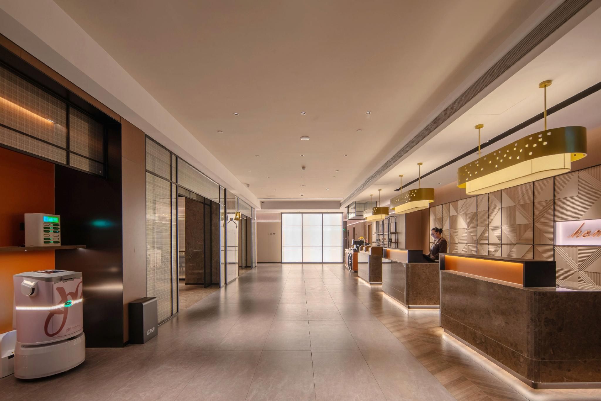 A hotel reception area with a long corridor, reception desks, and a vending machine.