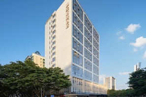 A high-rise building with a modern architectural design, featuring a grid of windows and a prominent vertical text on the facade. - Homeinn Select (Shenzhen)