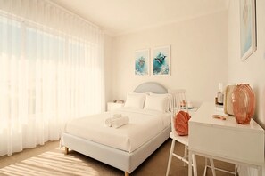 Een hotelkamer met een bed, een bureau, een stoel en kunst aan de muur.