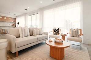 Una sala de estar moderna con un sofá, sillones, una mesa de centro y un comedor.