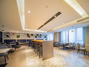 Un vestíbul d'hotel modern amb una barra central, zones d'estar i obra decorativa a la paret.
