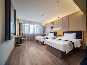 Habitació d'hotel amb dos llits, un escriptori i una cadira.