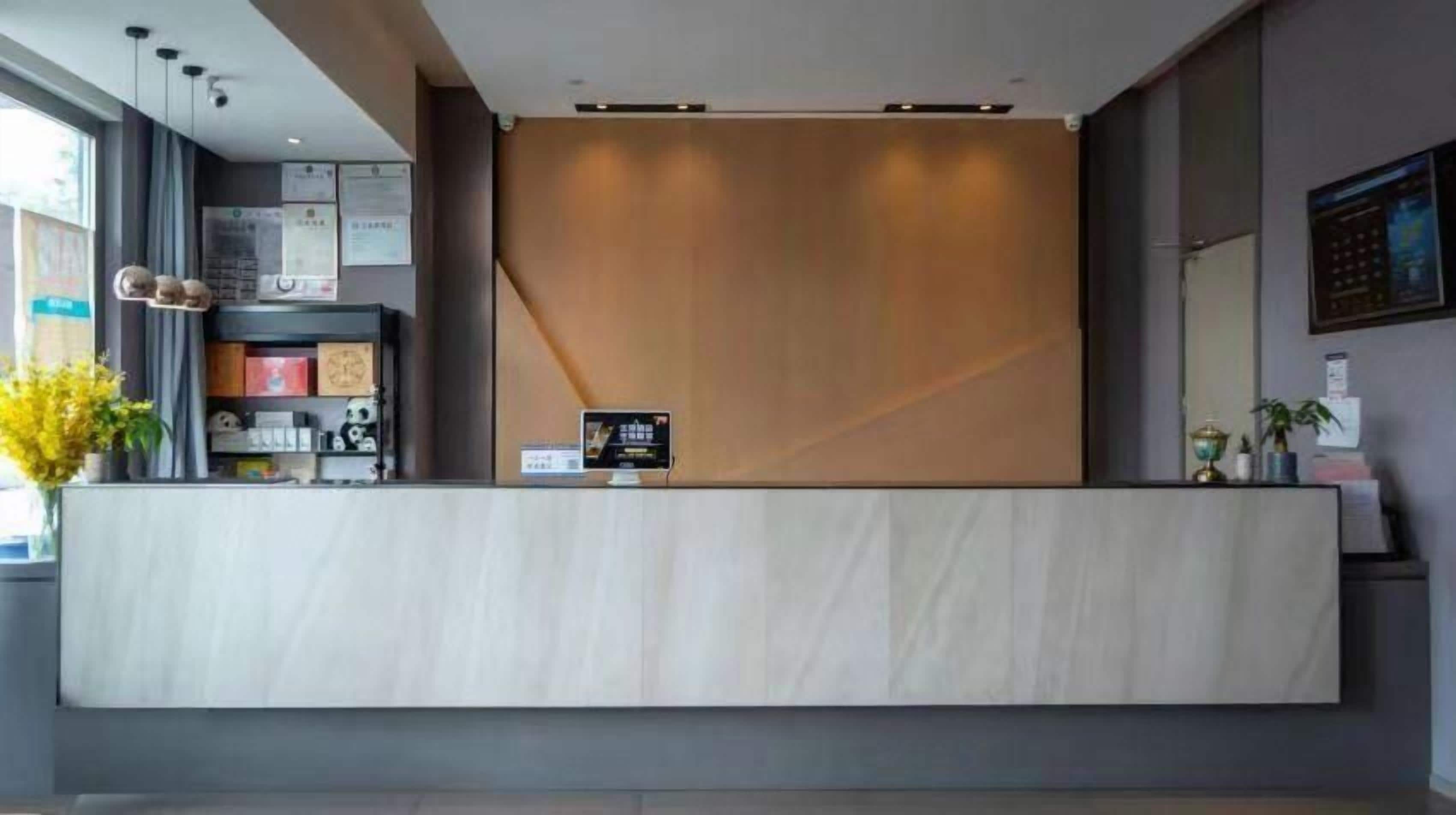 Een receptiebalie met een modern design, een digitaal scherm en een plant aan de linkerkant.