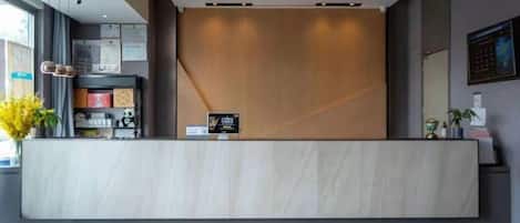 A reception desk with a modern design, a digital display, and a plant on the left.