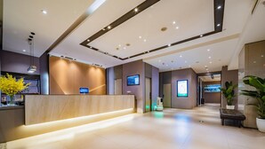Un moderno vestíbulo de hotel con una recepción, pantallas digitales y un piso de baldosas limpias.