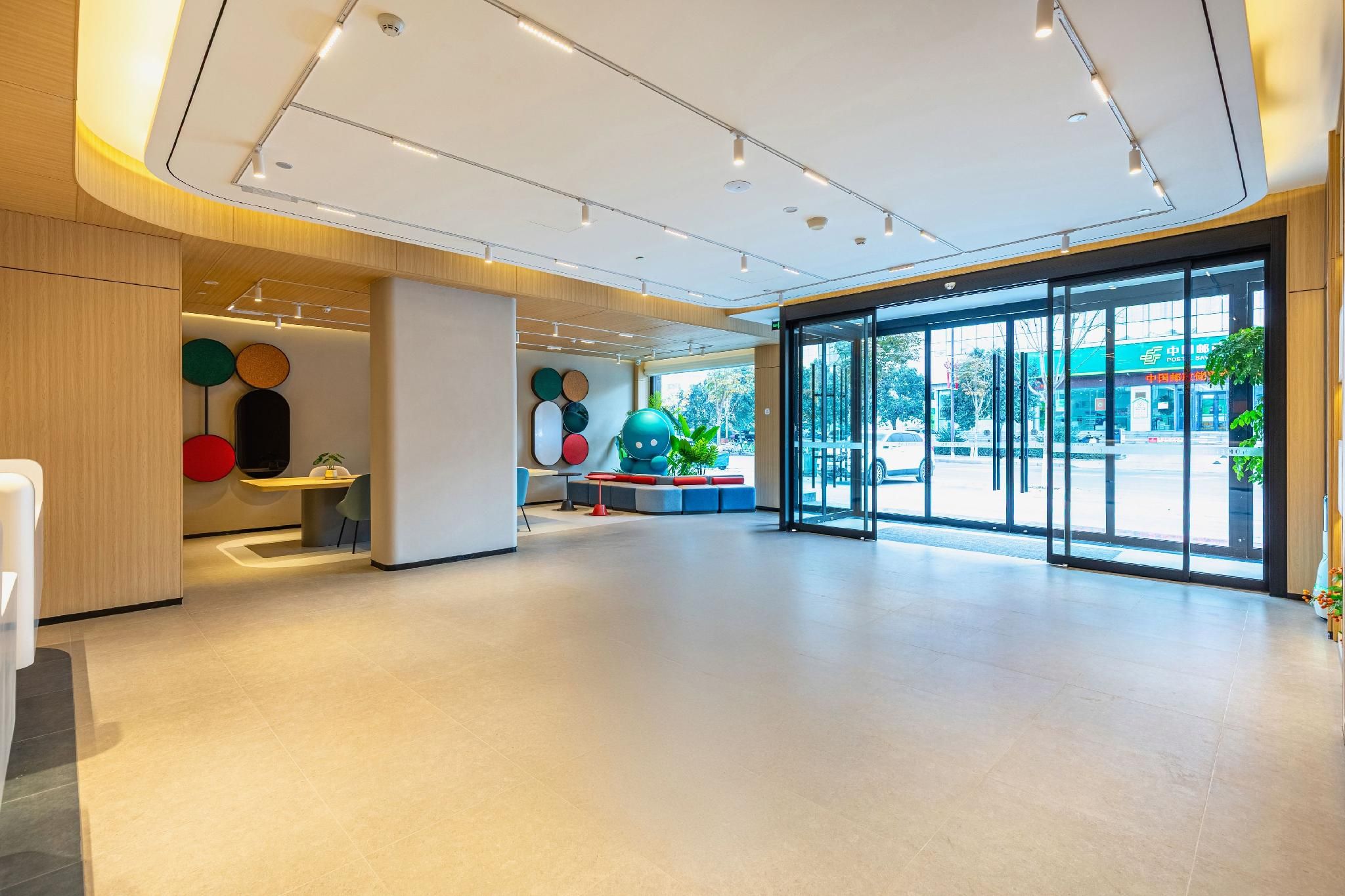 A spacious lobby with a modern design, featuring a large seating area, a reception desk, and a view of the outside through large glass doors.