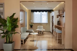 A modern living room with a sofa, a coffee table, and a dining area with chairs and a small table.