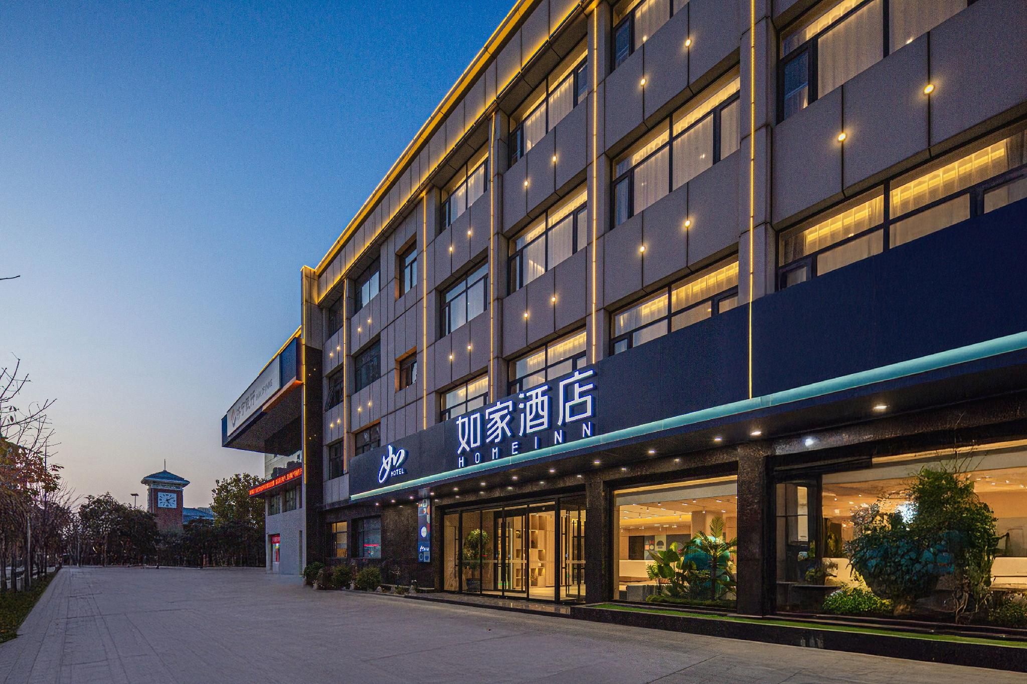 A hotel with a modern facade, large windows, and a sign indicating it is a home inn.