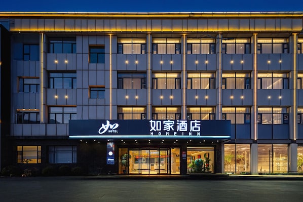A hotel with a modern facade, multiple floors, and illuminated windows.