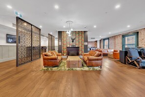 A spacious lobby with leather sofas, a fireplace, and a patterned wall. - High-Rise 1-Bed Apartment Near Southern Cross (Melbourne)