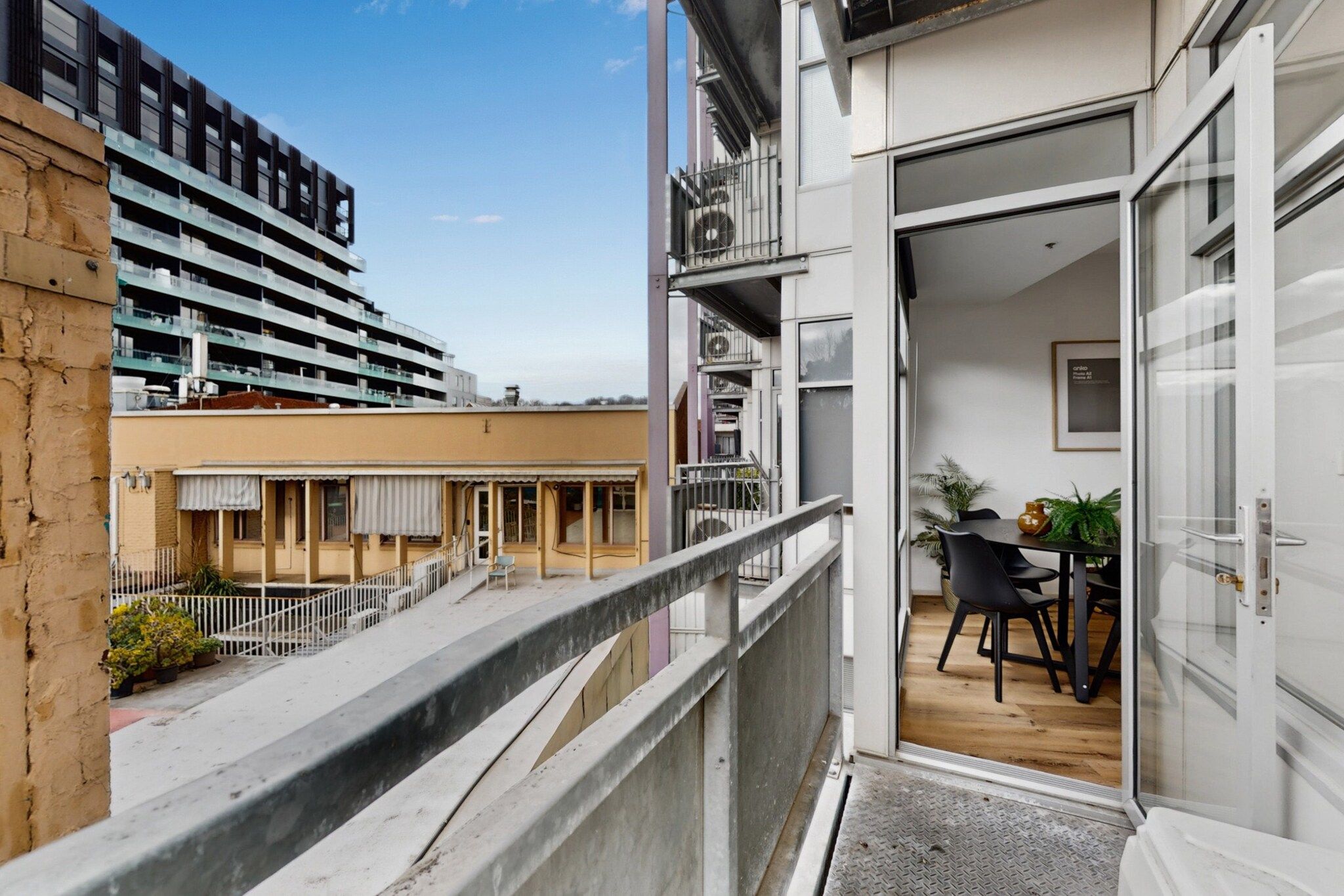 A balcony with a view of a building and a table with chairs.
