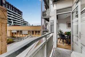 A balcony with a view of a building and a table with chairs. - Stylish 2-Bed Apartment Near Melbourne Central (Carlton)