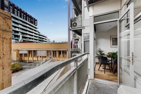 A balcony with a view of a building and a table with chairs. - Stylish 2-Bed Apartment Near Melbourne Central (Carlton)