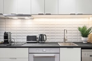 A modern kitchen with white cabinets, a black countertop, a coffee maker, a toaster, and a sink. - Melbourne 1-Bed Apartment Flinders Street (Melbourne)