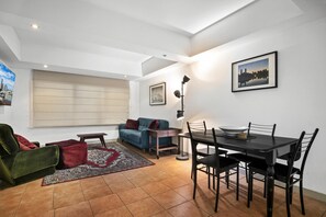 Una sala moderna con un sofá, una mesa de comedor y una pintura de un paisaje urbano.