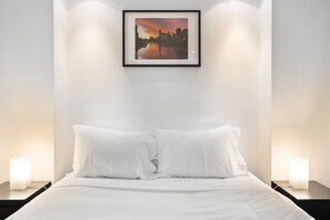 Una habitación de hotel con una cama, dos lámparas de noche y un cuadro en la pared.