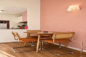 A dining area with a round table, four chairs, and a wall-mounted light fixture. - Empire Theatre Loft |Your Colourful Melbourne Stay (Melbourne)