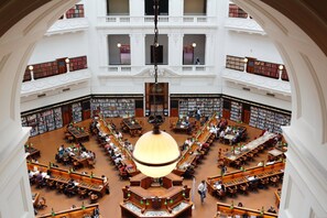 A multi-level library with numerous bookshelves, reading tables, and a central chandelier. - Empire Theatre Loft |Your Colourful Melbourne Stay (Melbourne)