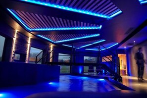 Un interior moderno con una escalera, ventanas amplias e iluminación azul.