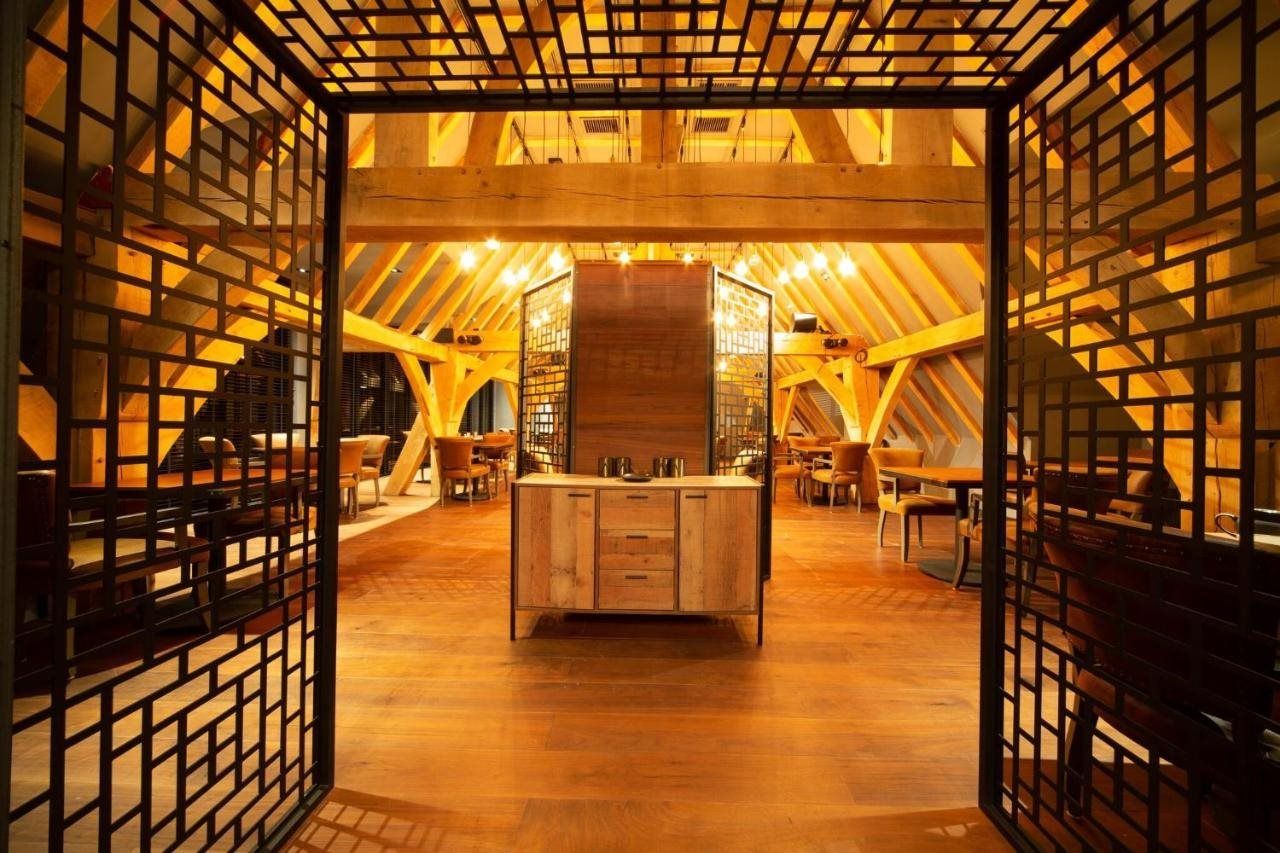 Un intérieur doté d’un comptoir central en bois, de poutres apparentes et d’une cloison à motifs géométriques.