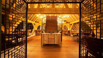 Un intérieur doté d’un comptoir central en bois, de poutres apparentes et d’une cloison à motifs géométriques.