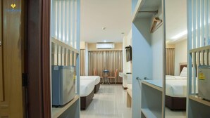 A hotel room with two beds, a desk, a chair, a television, and an air conditioning unit. - Taragrand Donmuang Airport Hotel (Thanyaburi)