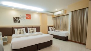 A hotel room with a large bed, a smaller bed, a bedside table, an air conditioning unit, and a window with curtains. - Taragrand Donmuang Airport Hotel (Thanyaburi)