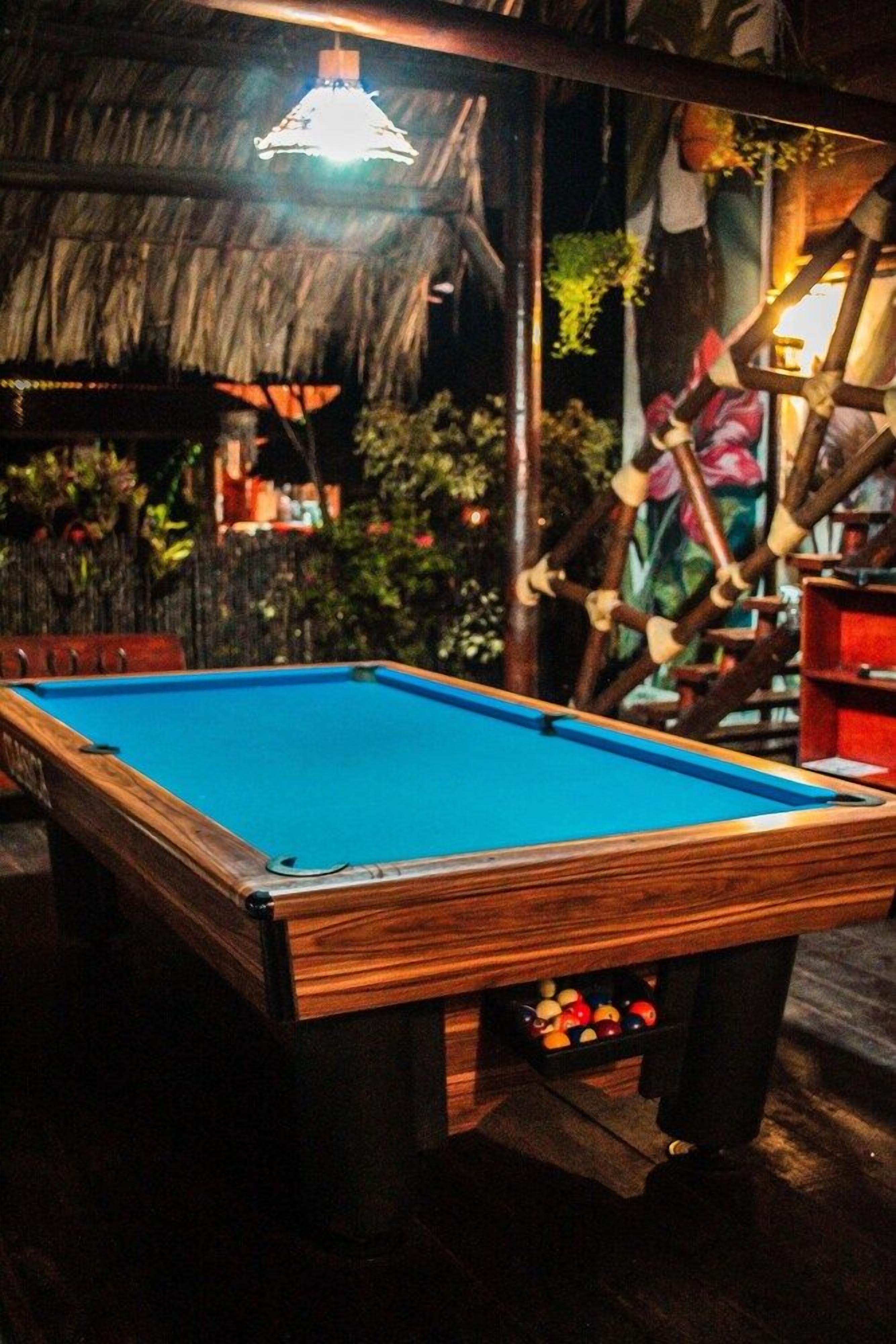 Una mesa de billar con superficie de fieltro azul, rodeada por un marco de madera.