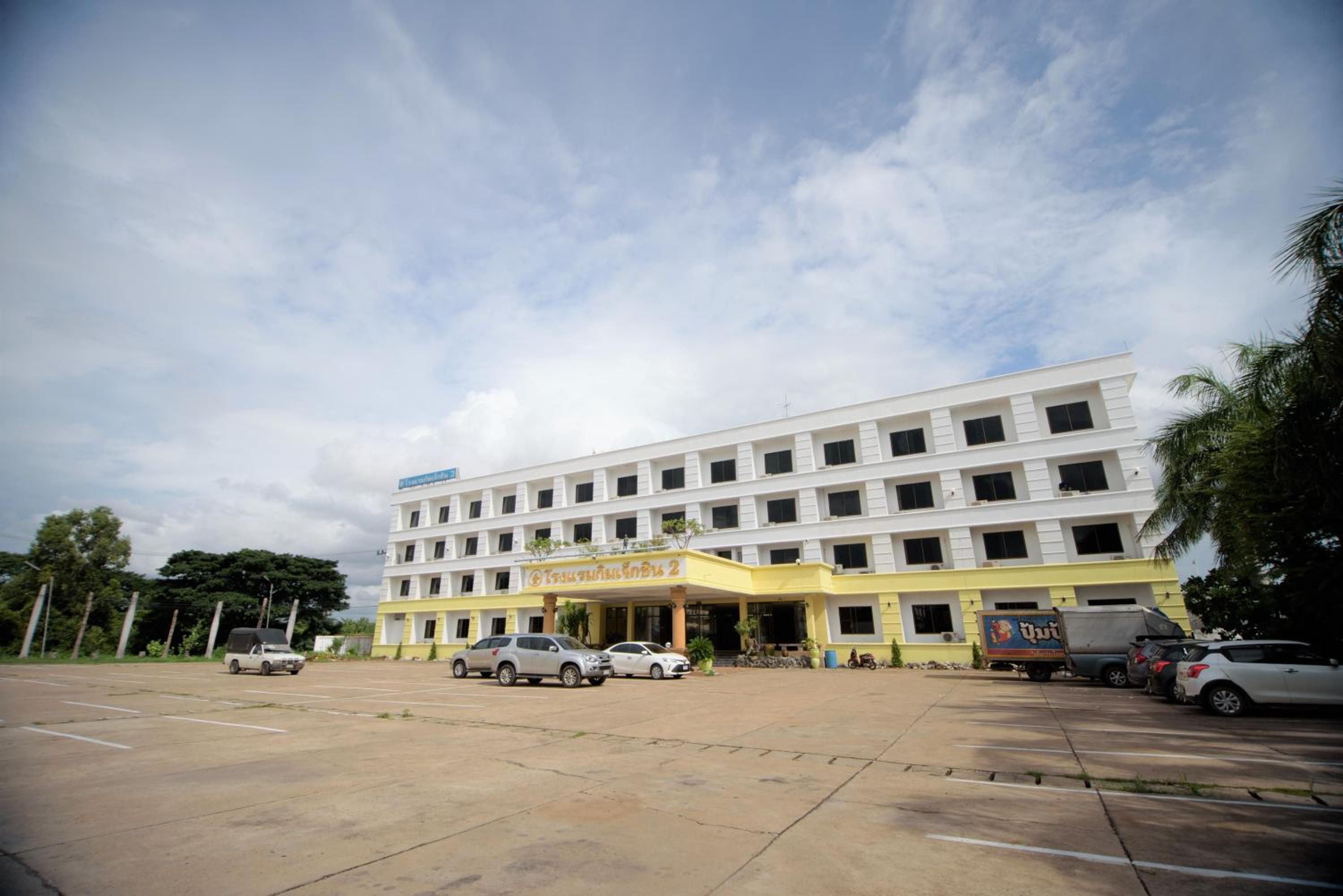 A multi-story building with a yellow entrance and several parked cars.