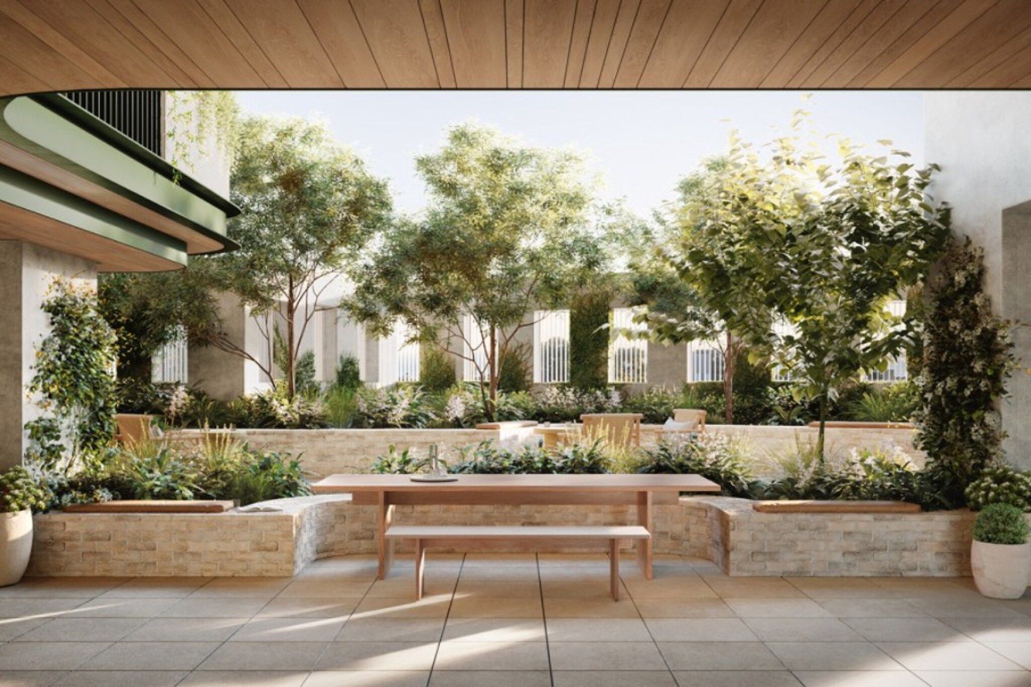 Un espace extérieur aménagé en patio, avec un banc en bois, des jardinières en pierre et une vue sur un bâtiment aux fenêtres grillagées.
