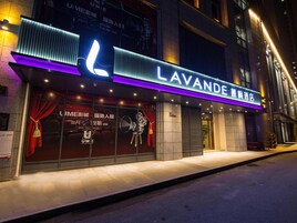 Fachada de hotel con un letrero llamativo, revestimiento de baldosas y acera frente a la entrada.