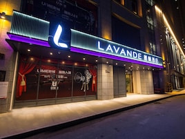 Fachada de hotel con un letrero llamativo, revestimiento de baldosas y acera frente a la entrada.