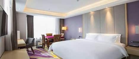 A hotel room with a large bed, a desk, a chair, and a television.