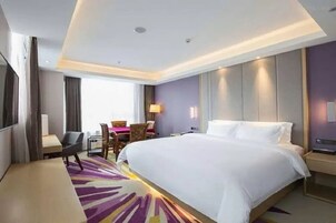 Una habitación de hotel con una cama grande, un escritorio, una silla y un televisor.