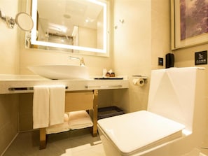 Un baño moderno con un lavamanos blanco, un espejo, un inodoro y un perchero para toallas.