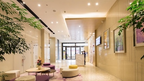 En modern hotellobby med en receptionsdisk, sittgrupper och konstverk på väggarna.