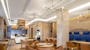 A modern restaurant interior with round tables, cushioned chairs, a bar area, and a seating section with blue cushions. - Kyriad Marvelous Hotel Shenzhen Nanlian Metro Station (Shenzhen)