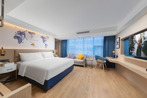 Una habitación de hotel moderna con una cama grande, un escritorio, una zona de estar y un ventanal con vista a la ciudad.
